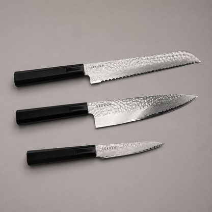 Three kitchen knives with textured silver blades and black handles, arranged diagonally on a neutral gray background.