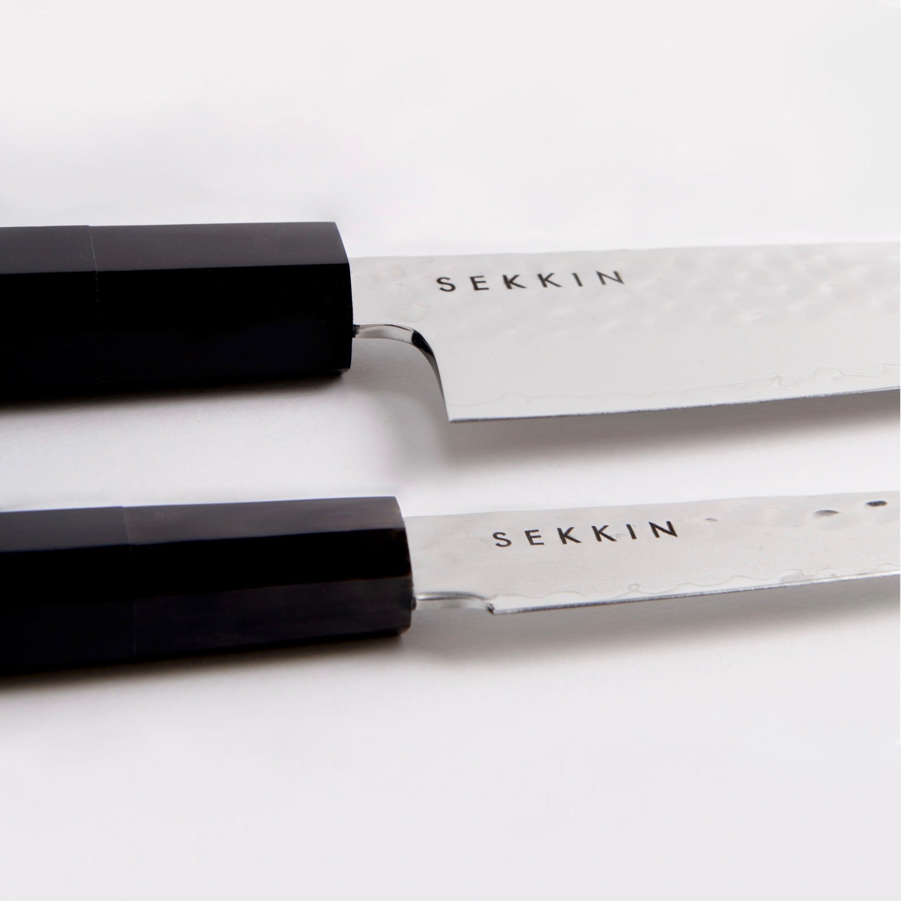 Two SEKKNIN knives with black handles on a white background