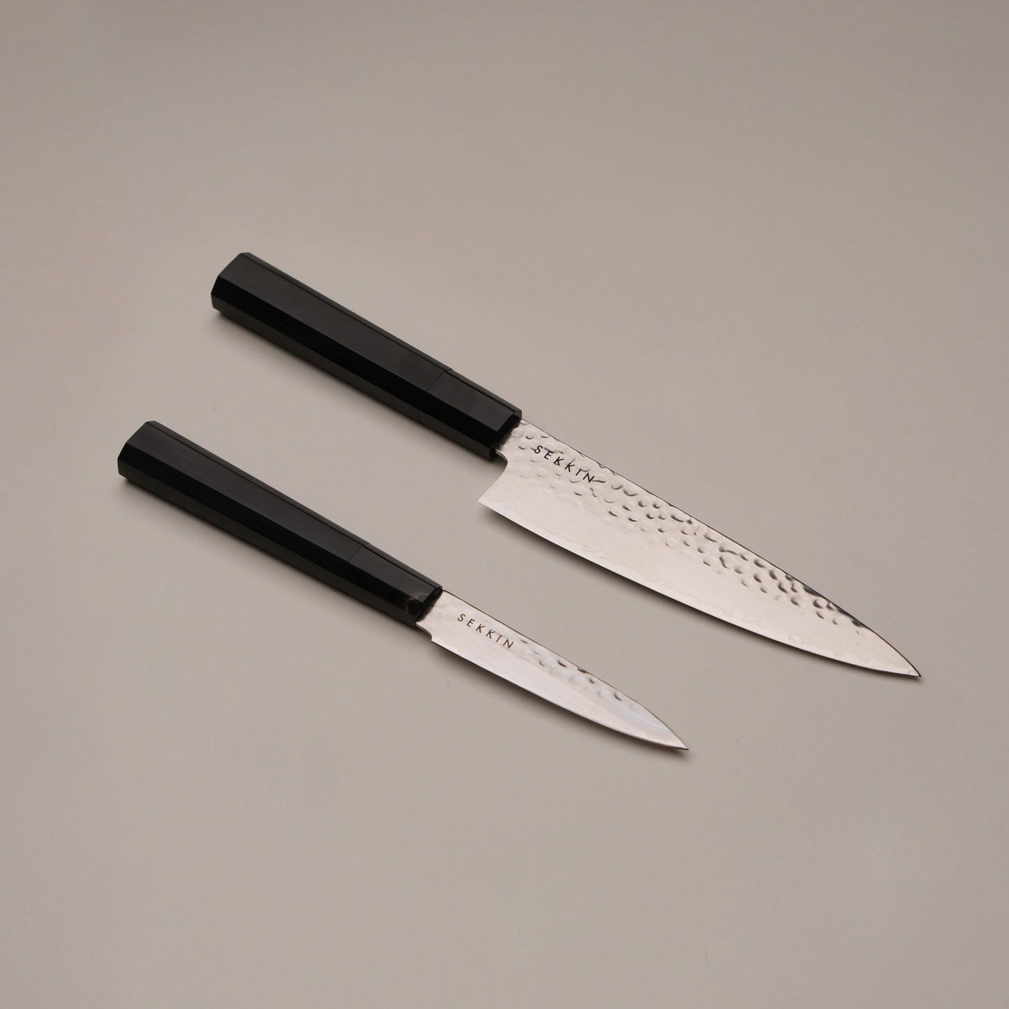 Two knives with black handles on a gray background