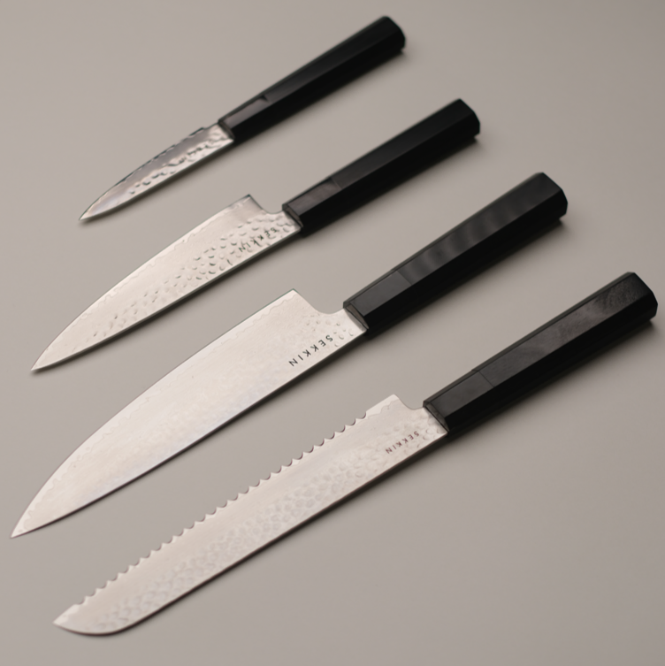 Set of four knives with black handles on a gray background