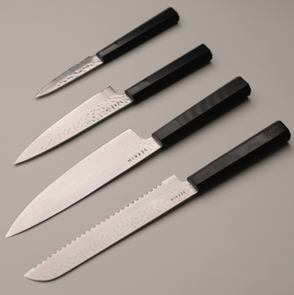 Set of four knives with black handles on a gray background